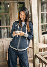 zaket & plover Denim Cardigan worn by a woman on a rustic porch
