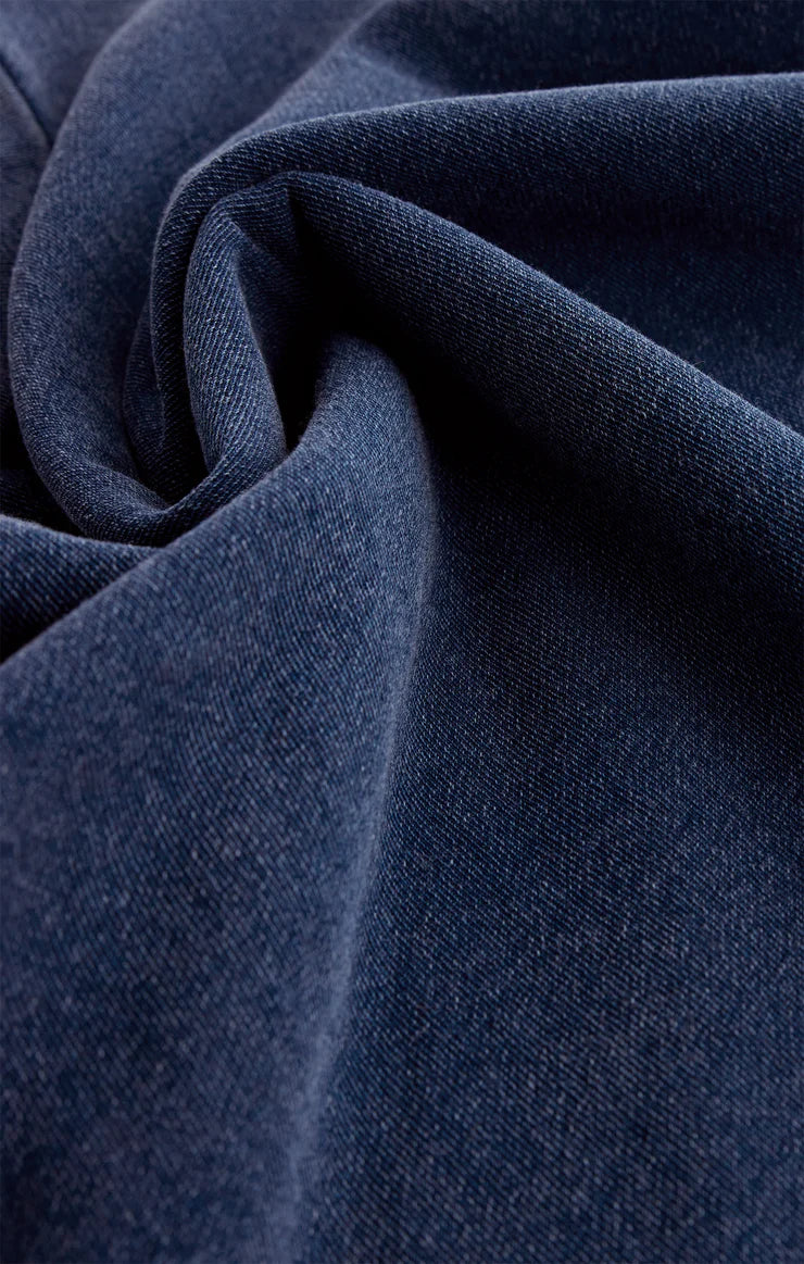 Close-up of soft indigo knit denim fabric with visible texture and raw edge detailing