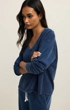 Woman wearing Z Supply Indigo Delphine Knit Denim Sweatshirt in soft indigo with relaxed fit and v-neck design