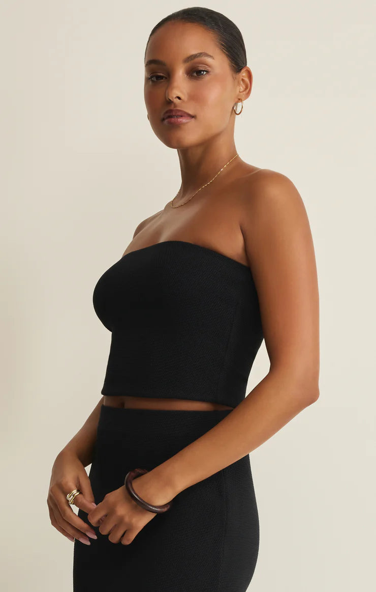 Model wearing a black Z Supply Caffari Tube Top Tank styled with matching skirt and gold jewelry accessories