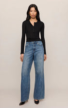Model wearing a black Rowena Fine Knit Sweater by z supply paired with blue wide-leg jeans and black shoes.