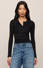 Woman wearing a Black Rowena Fine Knit Sweater by z supply with button detail and long sleeves paired with blue jeans.
