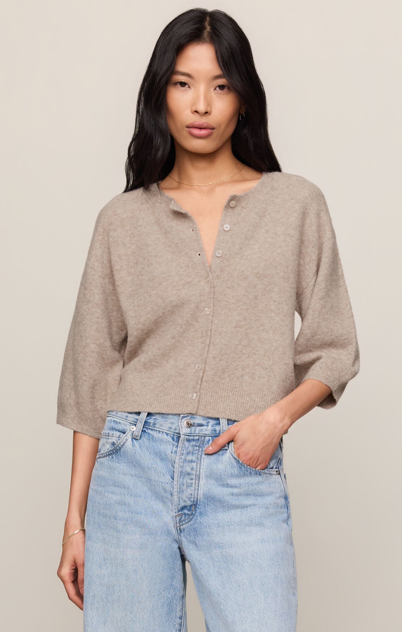 Woman wearing a Natural Heather Valor Cardigan by z supply in soft beige with light blue jeans against a neutral background