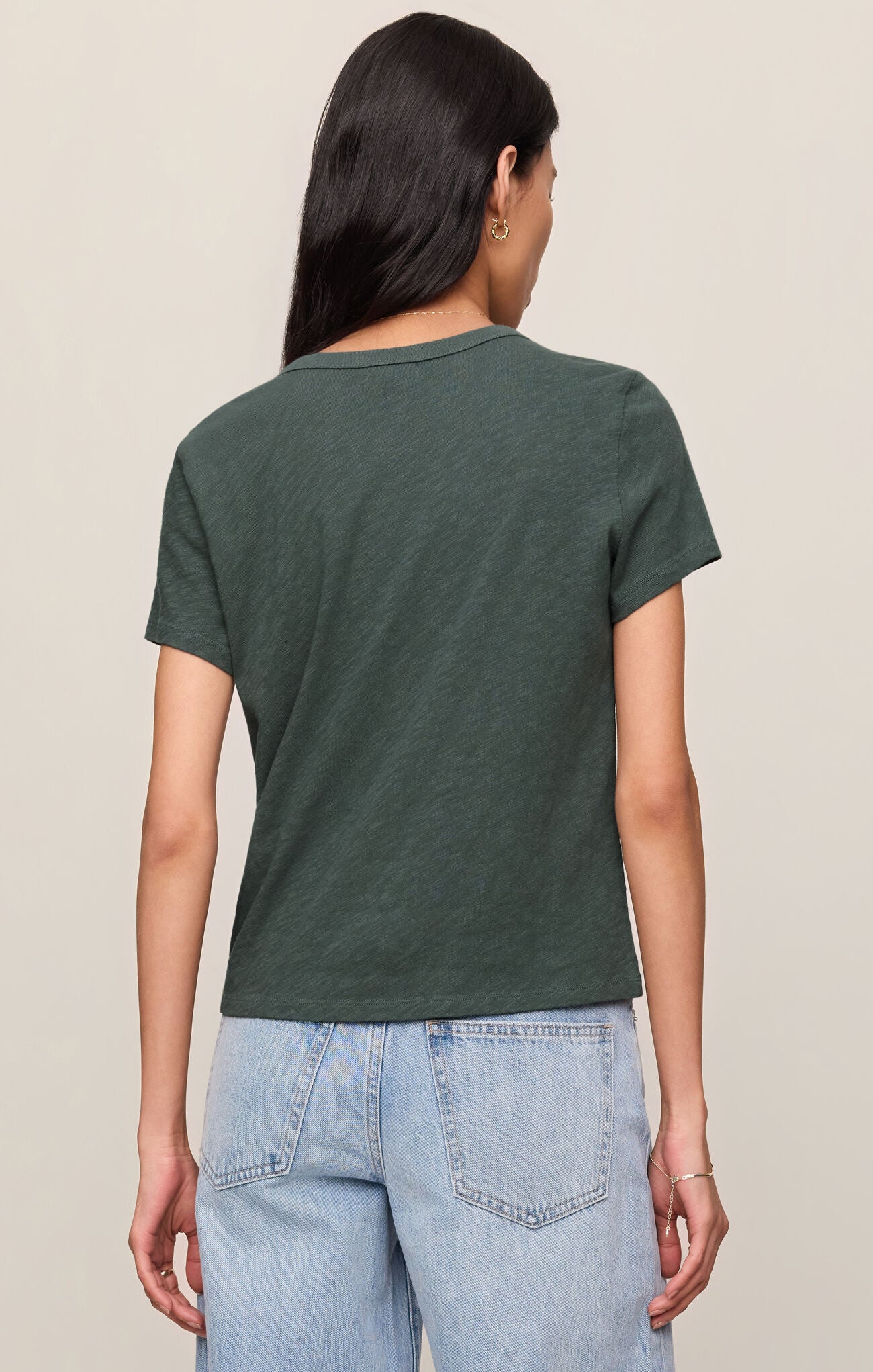 Woman wearing the back view of the Emerald Cove Junie Slub Tee Shirt by z supply in green with light-wash jeans