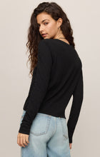 Woman wearing black Junie Long Sleeve Tee by z supply with light blue jeans, posing with back turned and head over shoulder