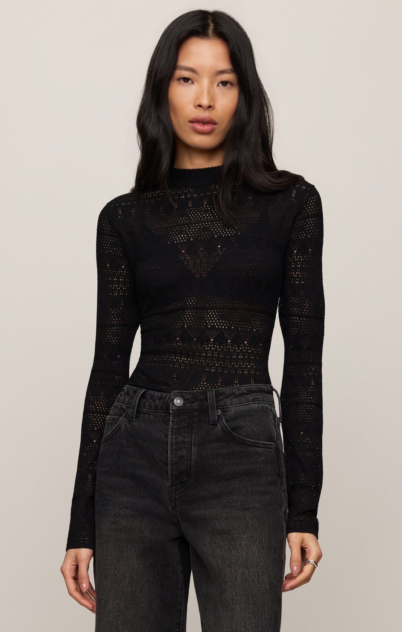 Woman wearing a fitted Black Avery Sweater Top by z supply with lace pattern and high neckline paired with dark jeans