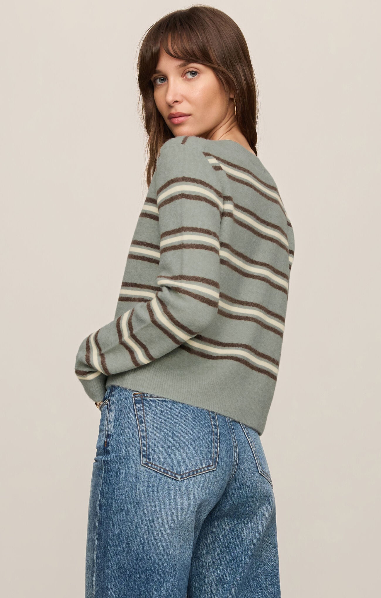 Woman wearing Aqua Cloud Medina Stripe Cardigan by z supply, soft knit with muted striped pattern and blue jeans.