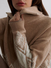 Woman wearing a light taupe jacquard half-zip sweater with ribbed collar and patterned sleeves closeup