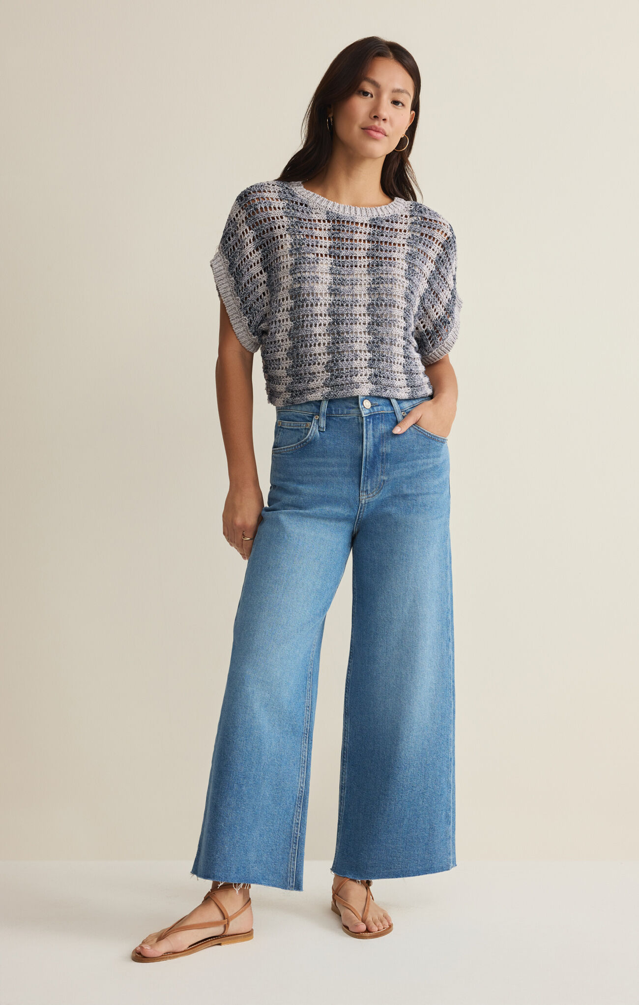 Woman wearing z supply Calypso Blue Indigo Ballast Crochet Stripe Top with loose weave and rolled sleeves styled with denim jeans