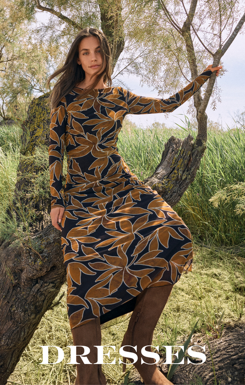 Woman in a floral print dress standing in a natural setting with 'DRESSES' text overlay.