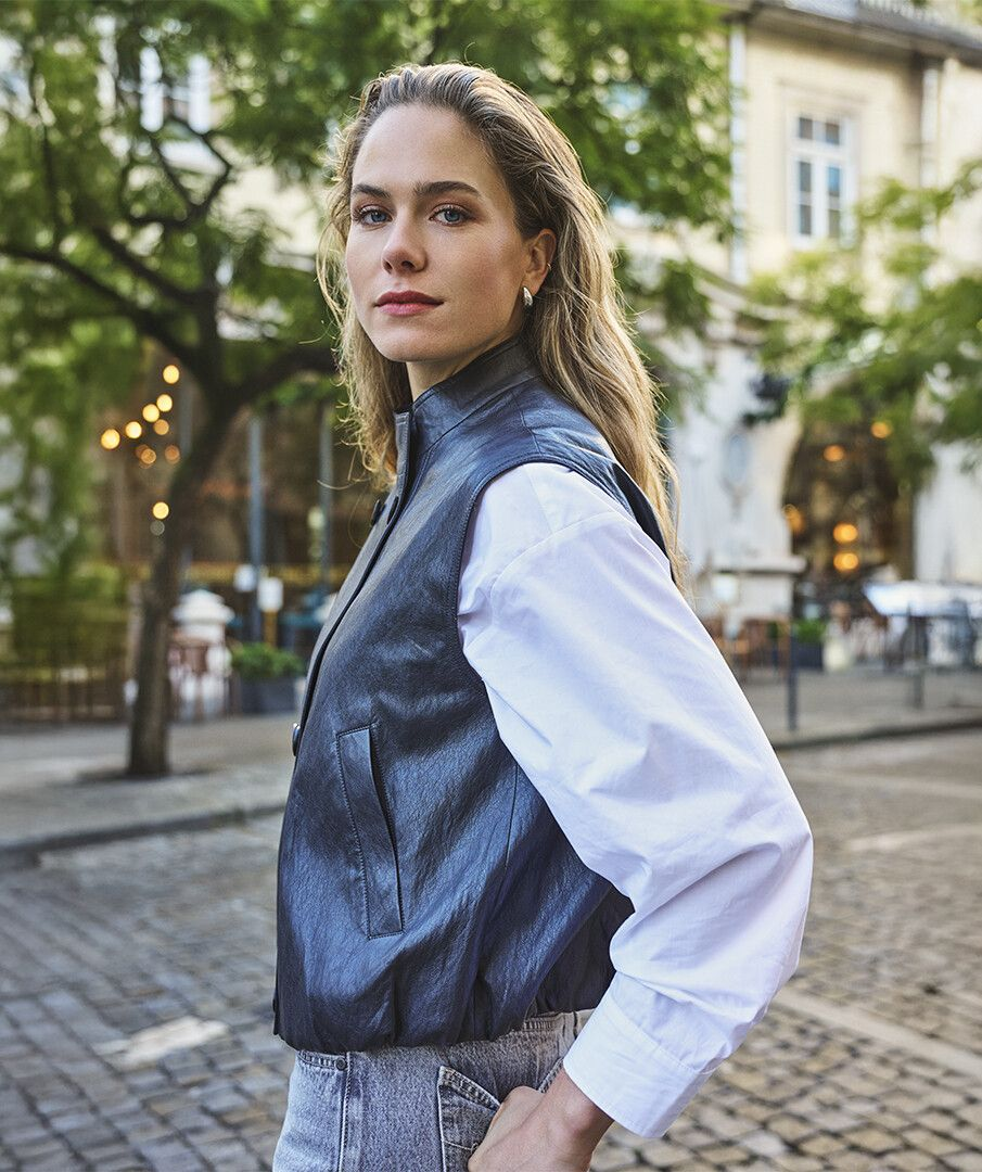 esqualo Dark Grey Faux Leather Vest worn over a white blouse outdoors