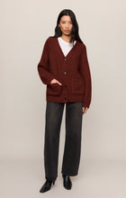 Woman wearing a deep red Velvet Rouge Whitmore Cardigan by z supply with black pants and ankle boots standing
