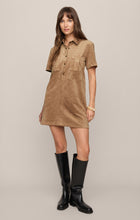 Woman wearing Light Sand Leone Suede Mini Dress by z supply with short sleeves and black knee-high boots on beige background