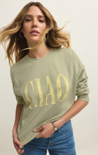 Woman with wavy hair wearing a light green sweatshirt with yellow 