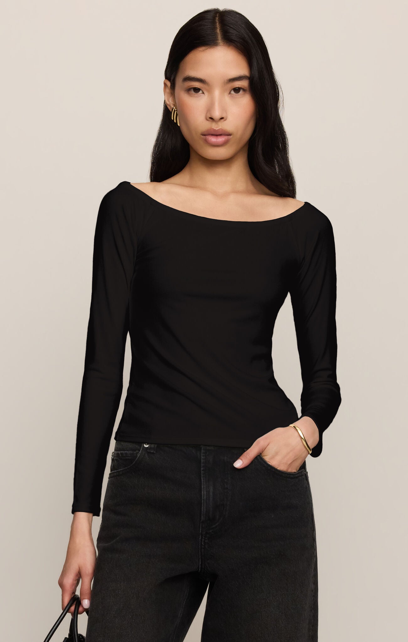 Woman wearing a Black Sabrina Top by z supply with long sleeves and a boat neckline paired with black jeans.