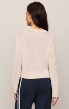 Woman wearing a Sandstone Varsity Stand in Sweater by z supply, shown from the back with navy striped pants
