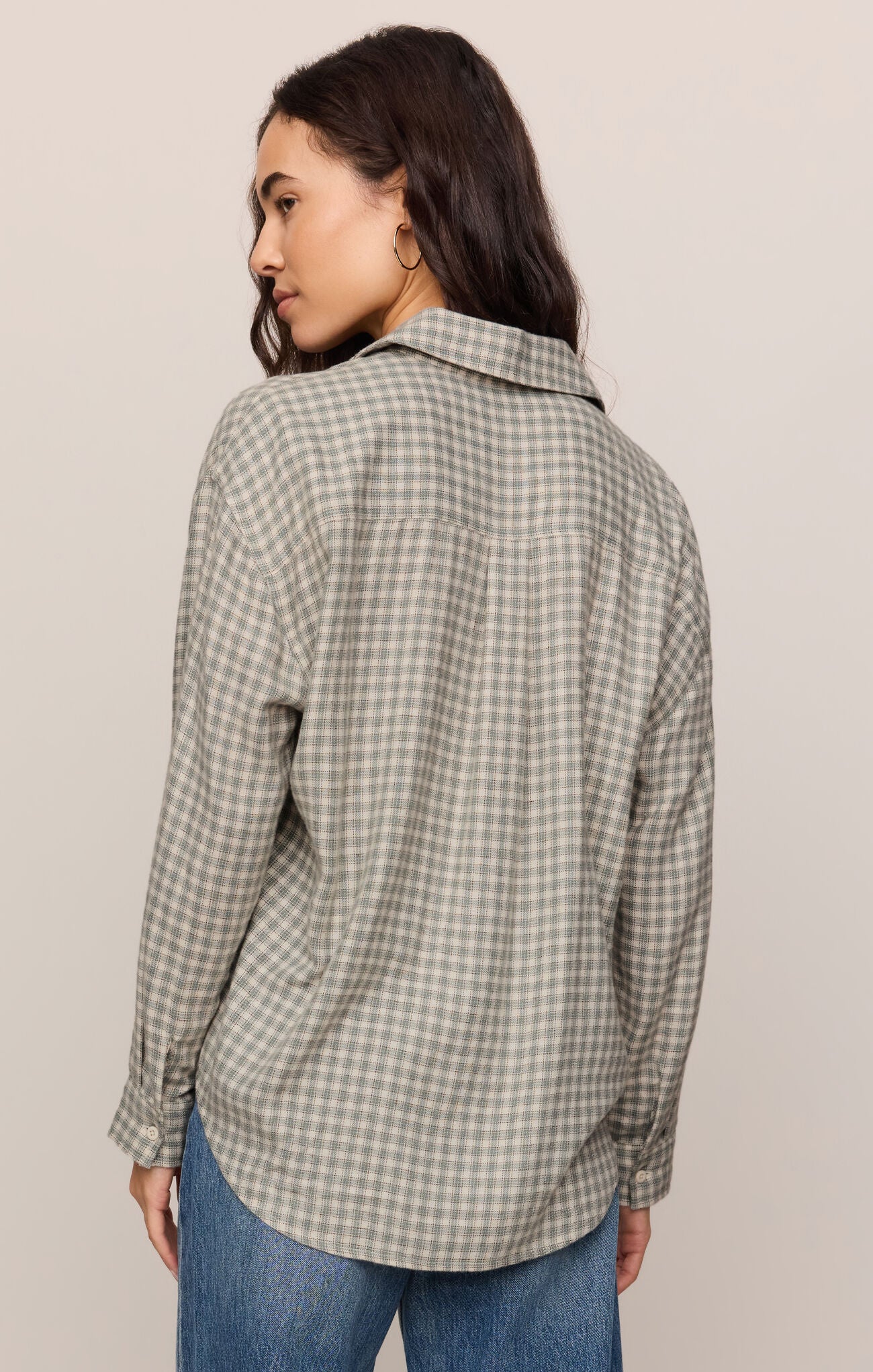 Woman wearing an Emerald Cove River Plaid Button Up by z supply, shown from the back in muted green plaid pattern.