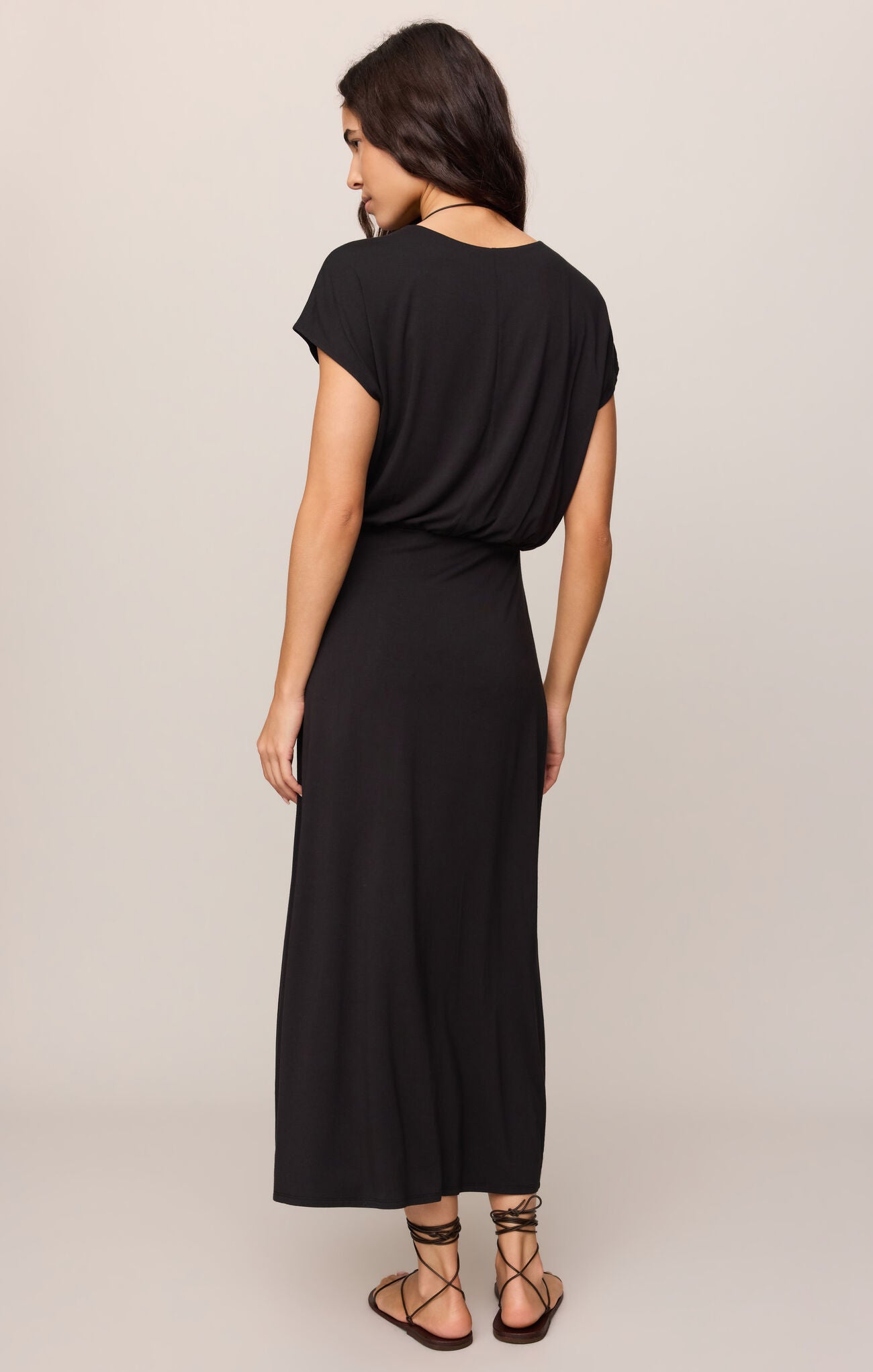 Woman wearing Black Anika Midi Dress by z supply, shown from back with short sleeves and relaxed fit silhouette