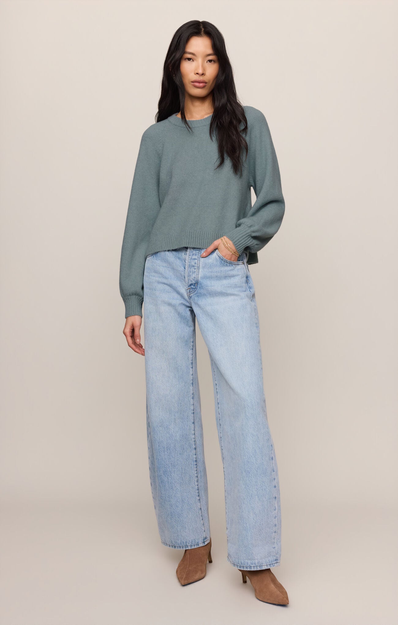 Woman wearing a Soft Succulent Coming Up Sweater by z supply in muted green with light blue wide-leg jeans and brown heels