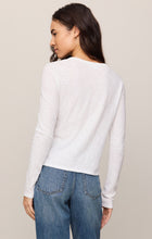 Woman wearing white Junie Long Sleeve Tee by z supply paired with blue denim jeans, back view.