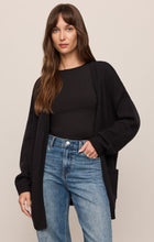 Woman wearing a relaxed black Sanborn Cardigan over a black top and blue jeans by z supply.