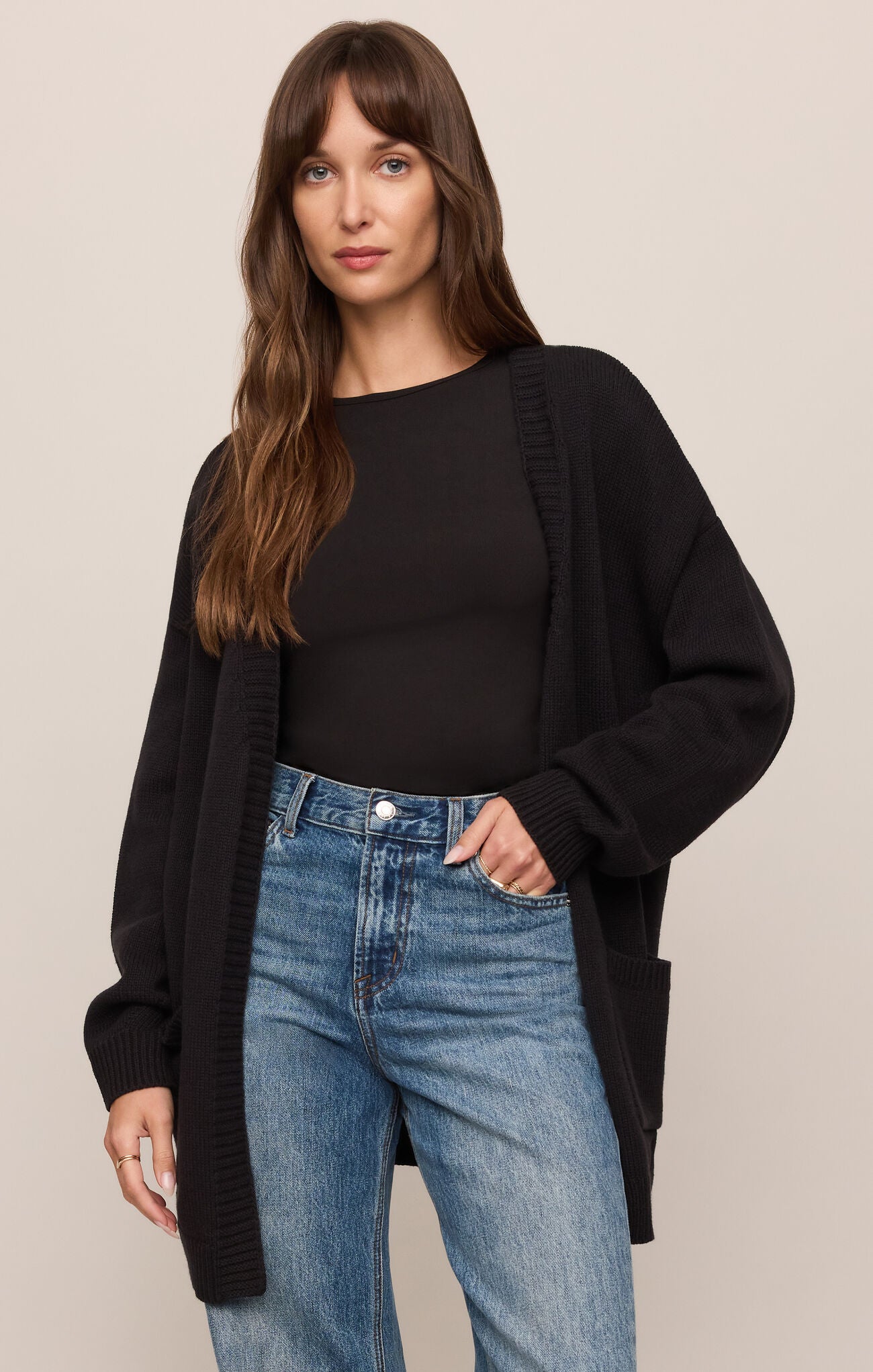 Woman wearing a relaxed black Sanborn Cardigan over a black top and blue jeans by z supply.