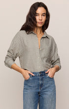Woman wearing Emerald Cove River Plaid Button Up by z supply paired with blue high-waisted jeans posing confidently