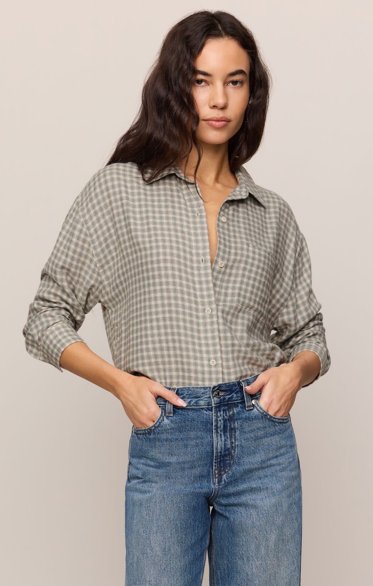 Woman wearing Emerald Cove River Plaid Button Up by z supply paired with blue high-waisted jeans posing confidently
