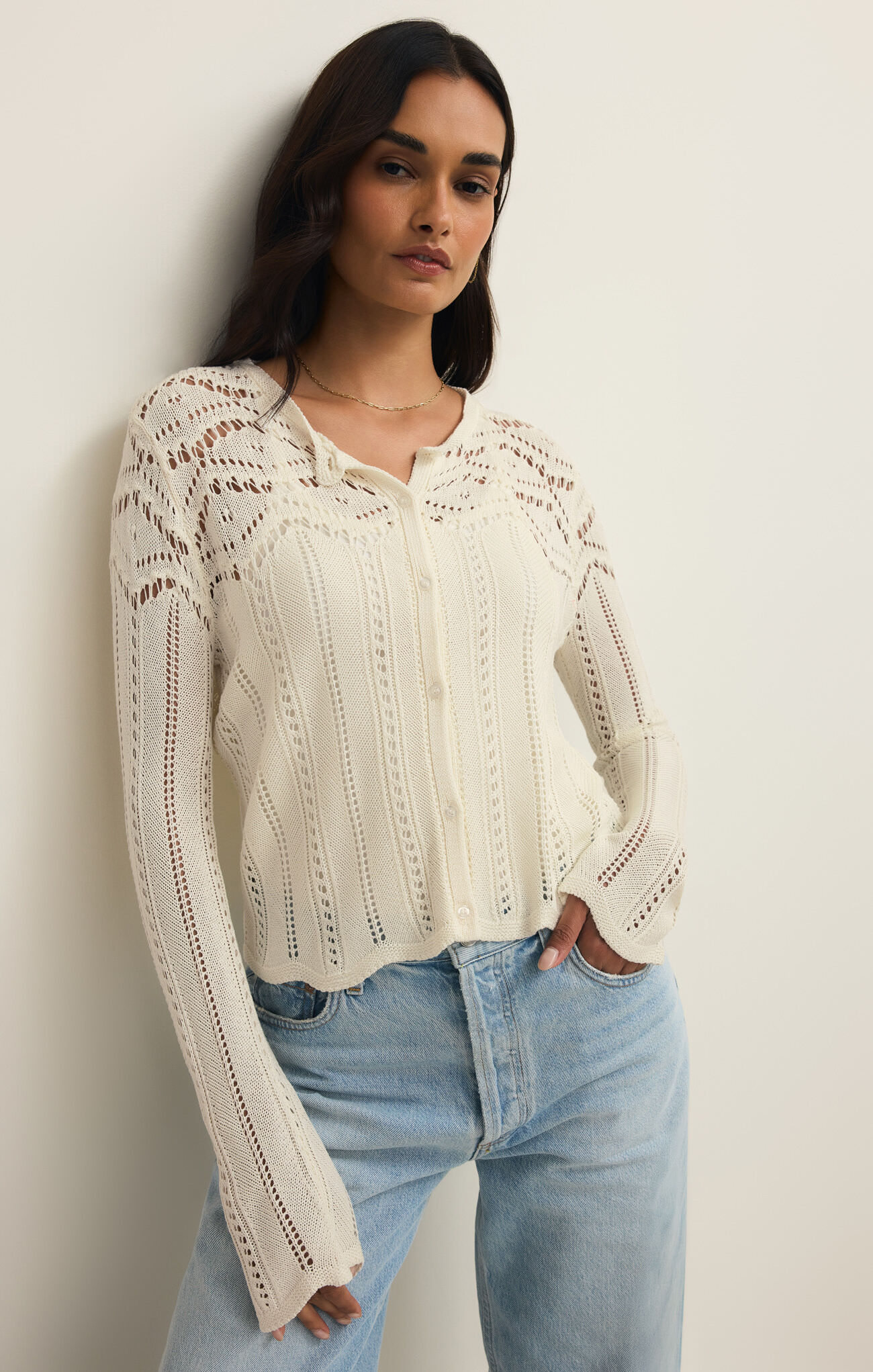Woman wearing an ivory Cloud Alycia Crochet Sweater by z supply with intricate crochet patterns and button front detail