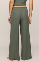 Back view of a person wearing olive green Monstera Waffle Pant by z supply with a ribbed texture and wide legs.