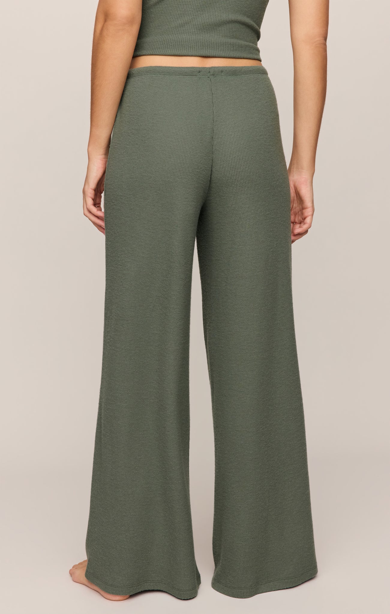 Back view of a person wearing olive green Monstera Waffle Pant by z supply with a ribbed texture and wide legs.