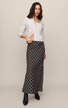 Woman wearing a white cardigan paired with an Ash Black Europa Plaid Skirt by z supply and black boots