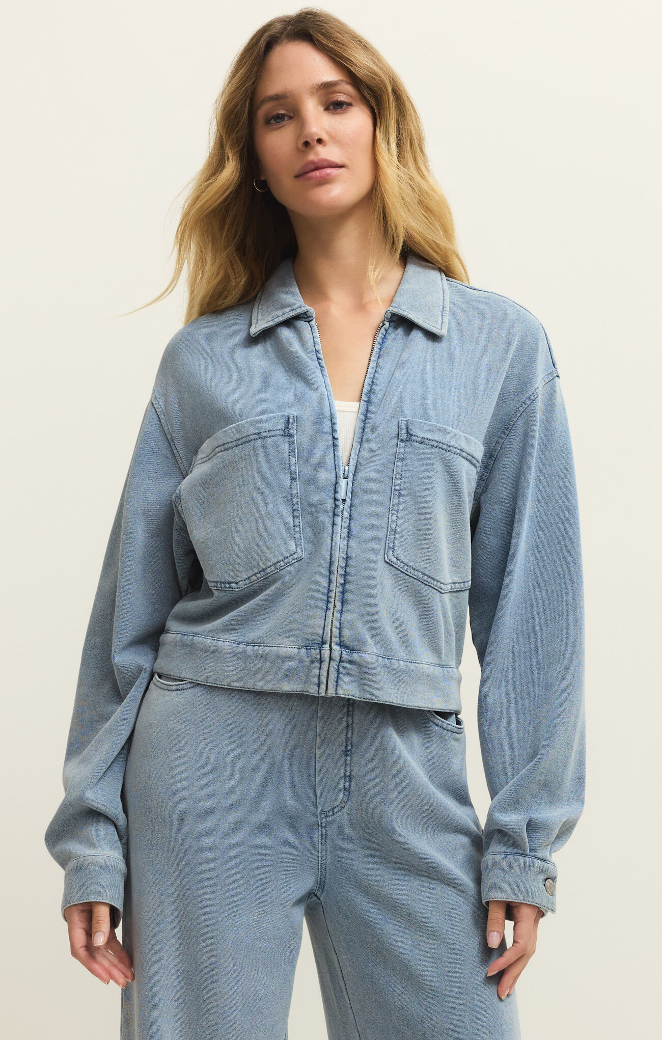 Model wearing Ocean Air Indigo Heritage Knit Denim Jacket by z supply in soft blue knit fabric with front pockets and collar design