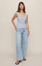 Woman wearing a light blue Skyline Ellie V Neck Tank by z supply paired with wide-leg jeans and sandals standing against a neutral wall