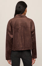 Rear view of a model wearing z supply Dark Chocolate All Day Cropped Suede Jacket with black jeans against neutral background