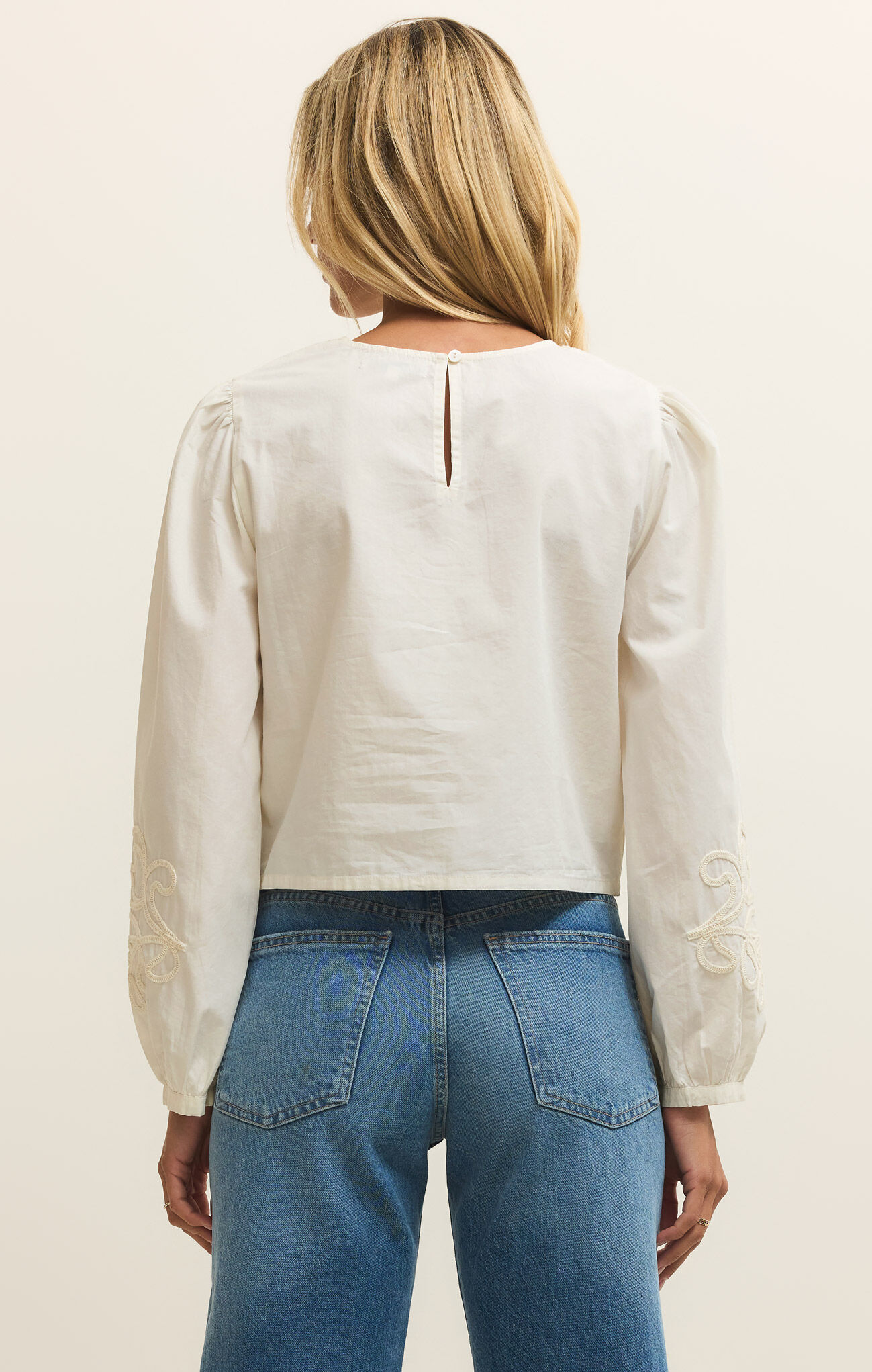 Back view of a woman wearing the White Tatiana Poplin Top by z supply with detailed sleeves and casual jeans