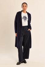 Molly Bracken Coat by Molly Bracken modeled in a navy long coat with wide leg trousers and graphic tee