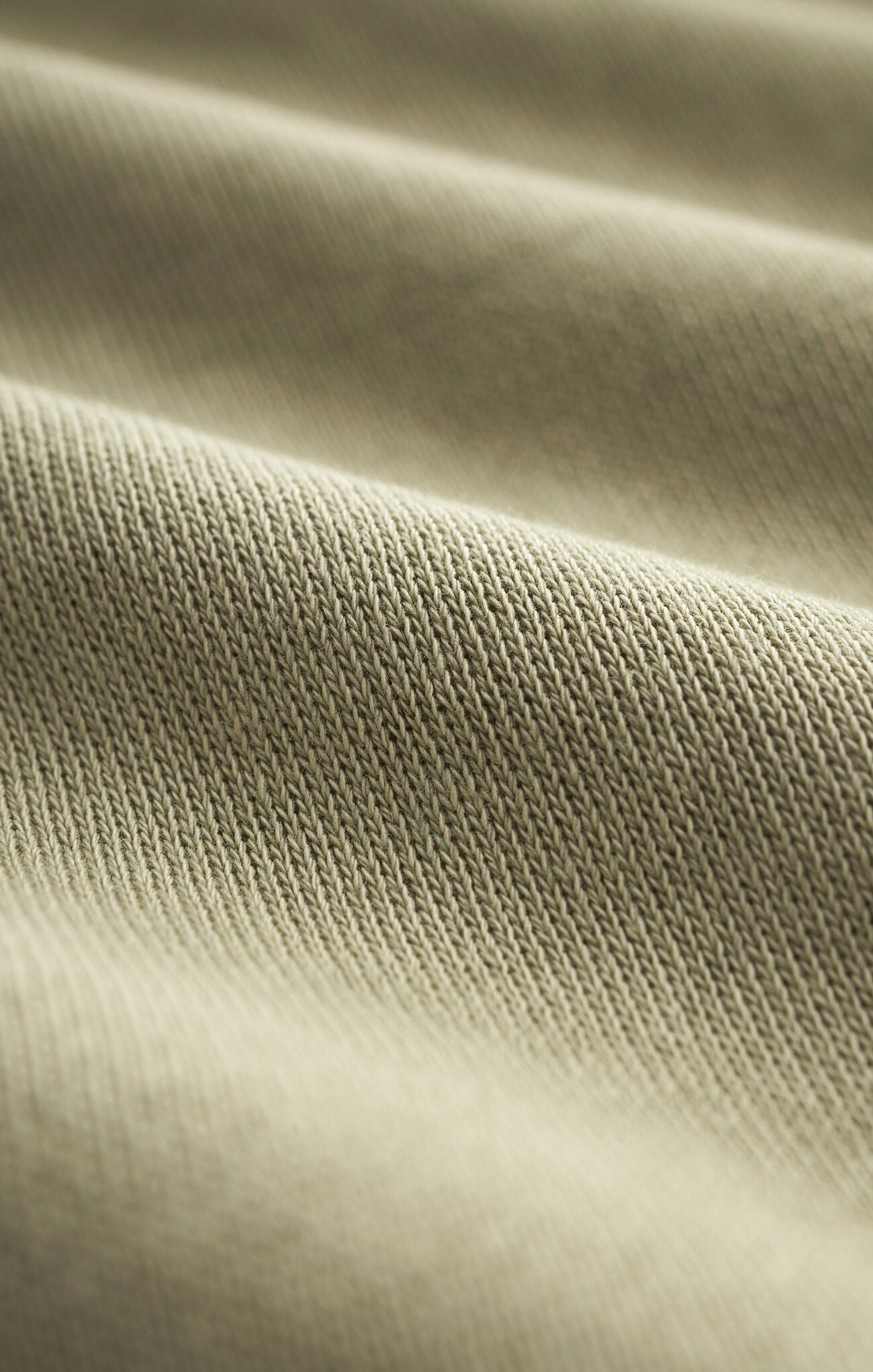 Close-up view of soft knit brushed fleece fabric in bay leaf green color showing texture and weave details