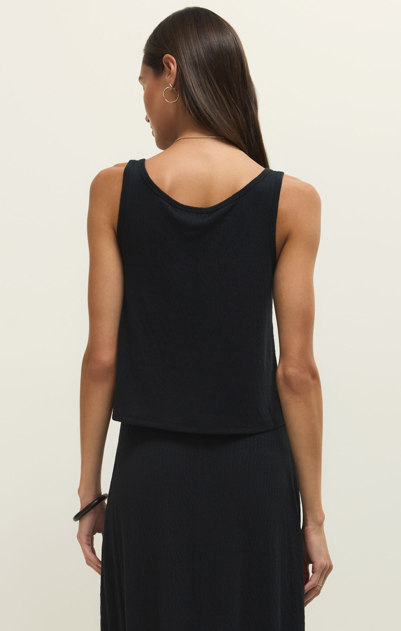Back view of a woman wearing the Black Joanna Tank by z supply with a sleek, textured fabric design