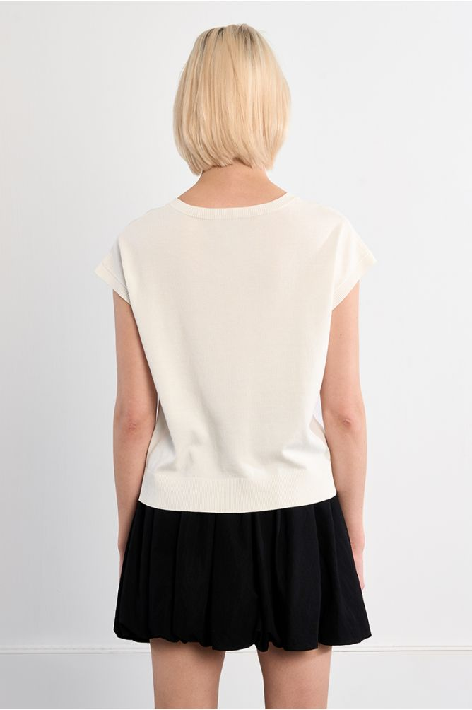 Back view of a woman wearing a white palm top by Molly Bracken with short sleeves and a black skirt.