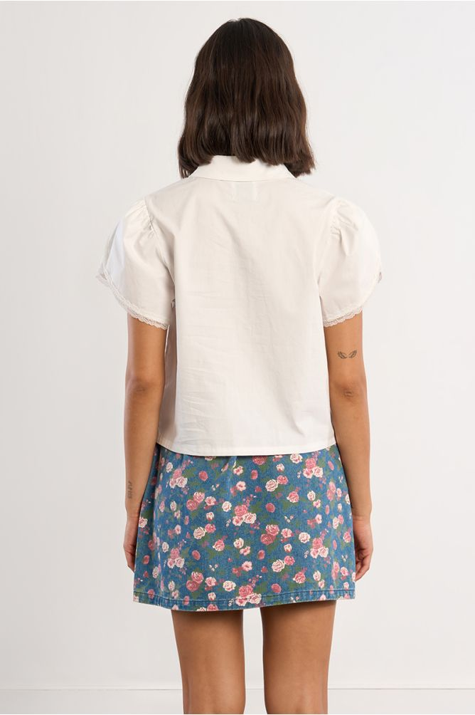 Back view of a White Grace Shirt with short puffed sleeves worn with a floral skirt by Molly Bracken