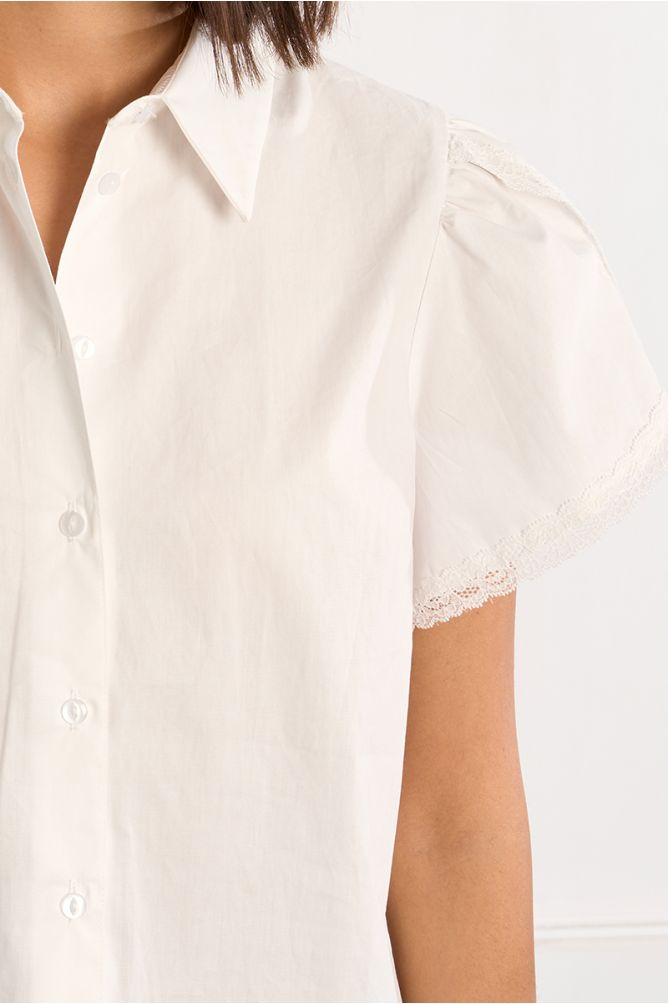 Close-up of a white short-sleeved White Grace Shirt by Molly Bracken with lace trim on sleeve edges and button front closure