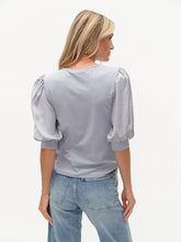 Woman wearing six/fifty Denim Solara Mixed Media Satin SS Top with puff sleeves and light blue jeans back view