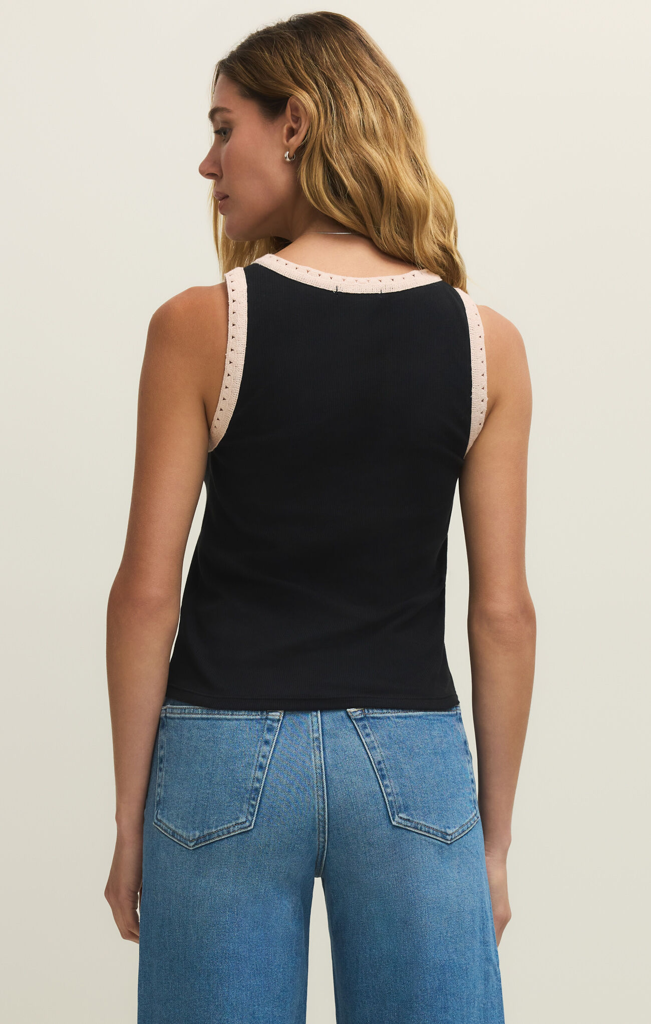 Woman wearing a black Clarke Rib Tank by z supply showing back view with contrast trim and blue denim jeans
