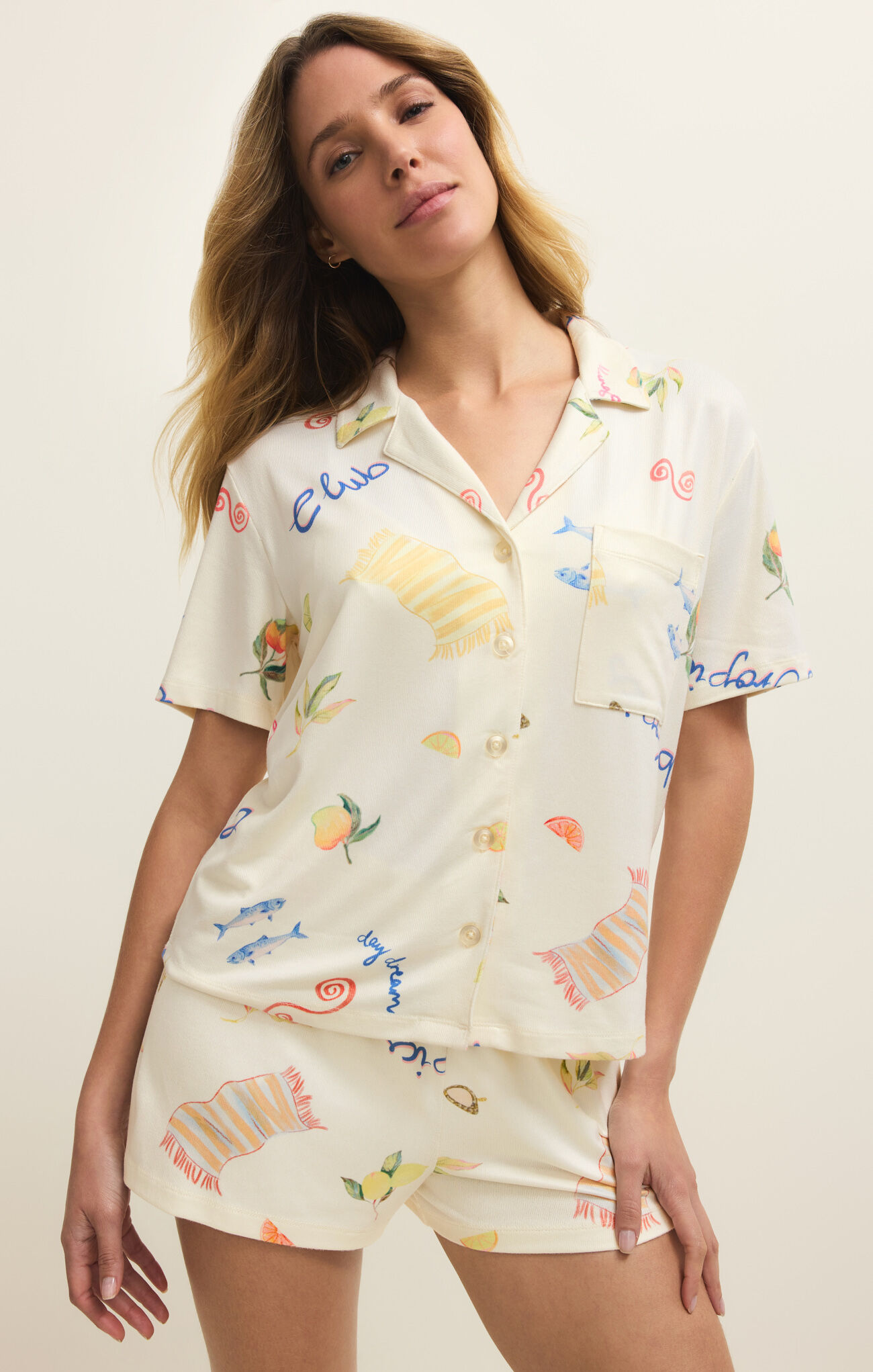 Woman wearing Vanilla Ice Beach Days PJ Top by z supply with colorful beach-themed prints on light fabric