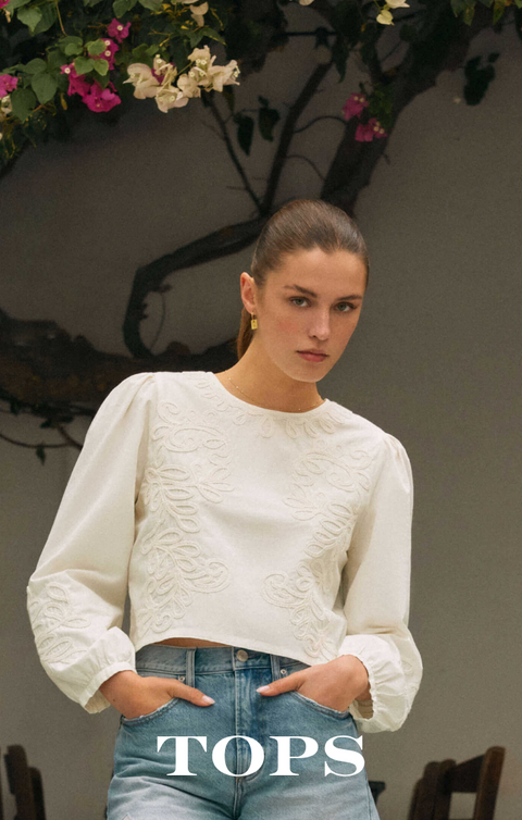 Close-up of a wrist wearing four beaded bracelets in gold and white pearl tones against a blurred background