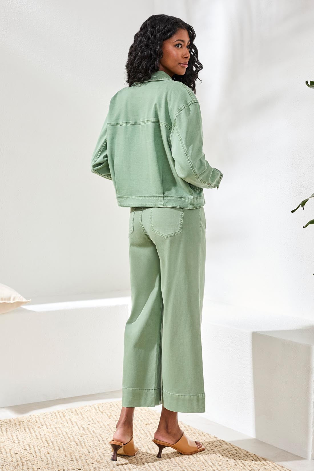 Model seen from behind wearing Tribal Comfort Stretch Denim Button-Front Jacket in muted green paired with matching wide-leg pants