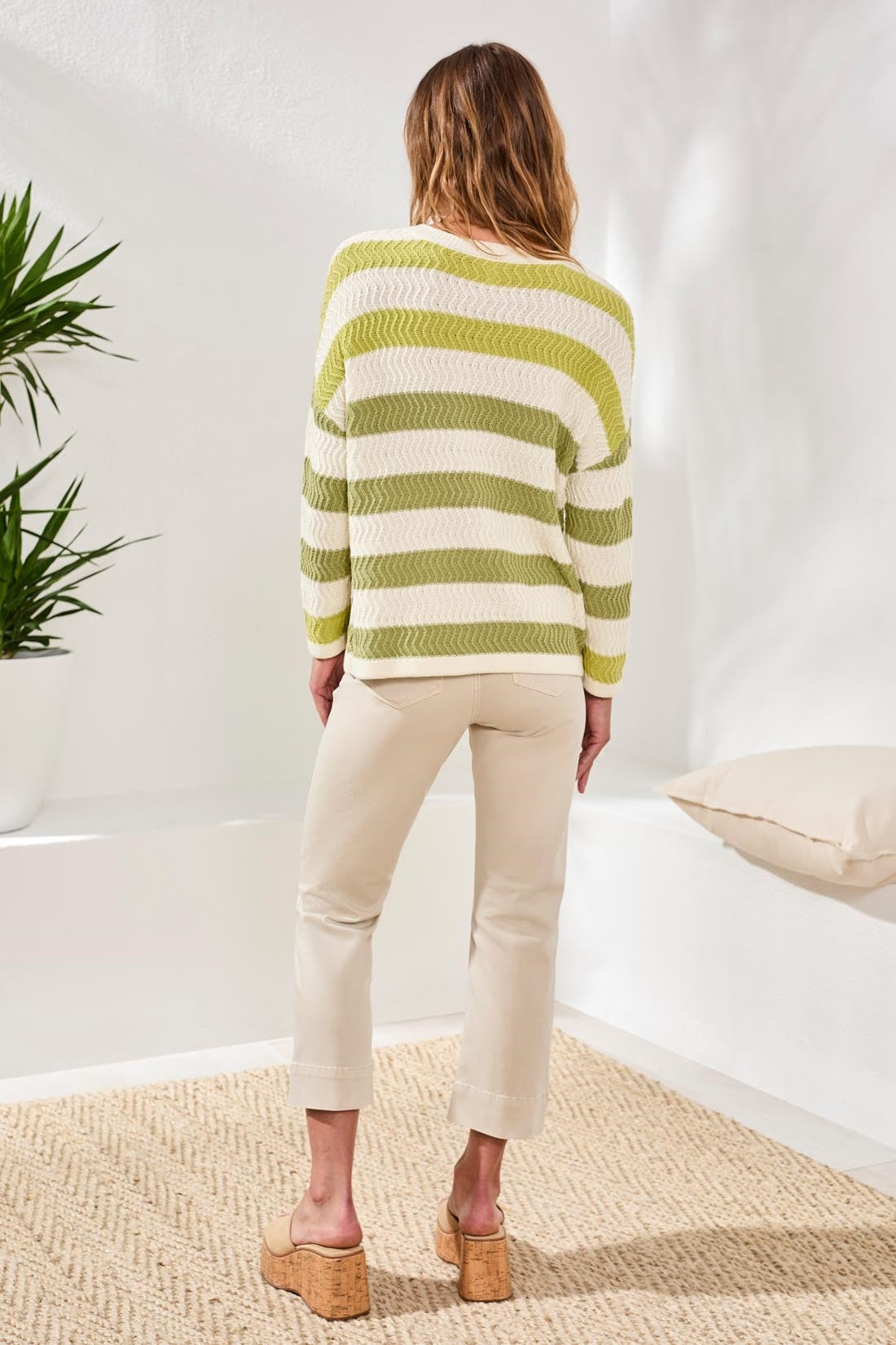 Rear view of woman wearing Tribal Kiwizest Crew Neck Drop Shoulder Sweater in green and cream stripes styled with beige pants