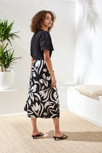 Woman wearing Tribal Printed Wrap‑Front Pull‑On Midi Skirt with bold black and white print in a bright indoor setting