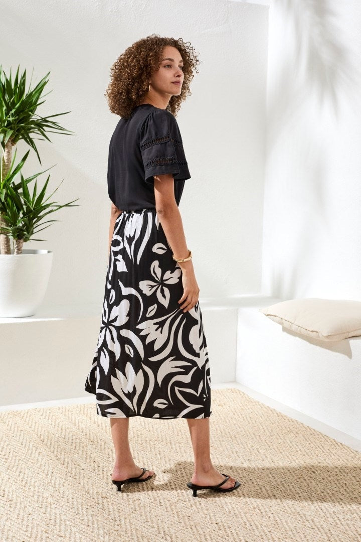 Woman wearing Tribal Printed Wrap‑Front Pull‑On Midi Skirt with bold black and white print in a bright indoor setting